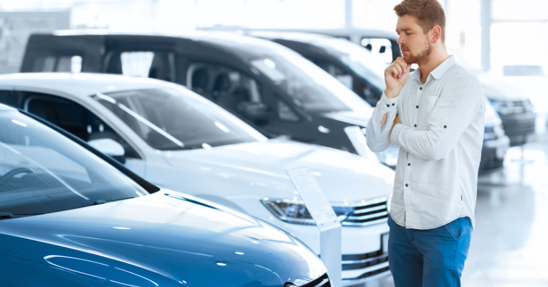 Young man considering car purchase at dealership
