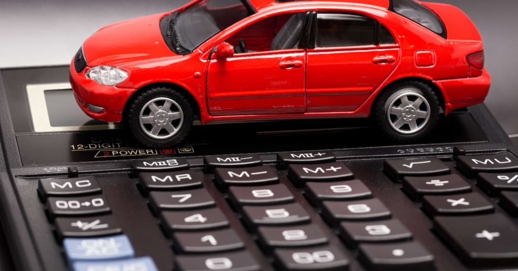 Red toy car placed on calculator