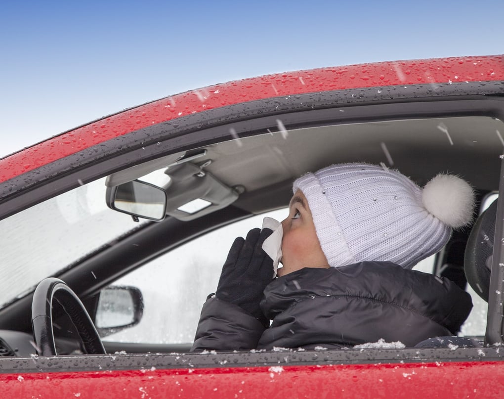 Girl sneezing in the car with a winter hat on